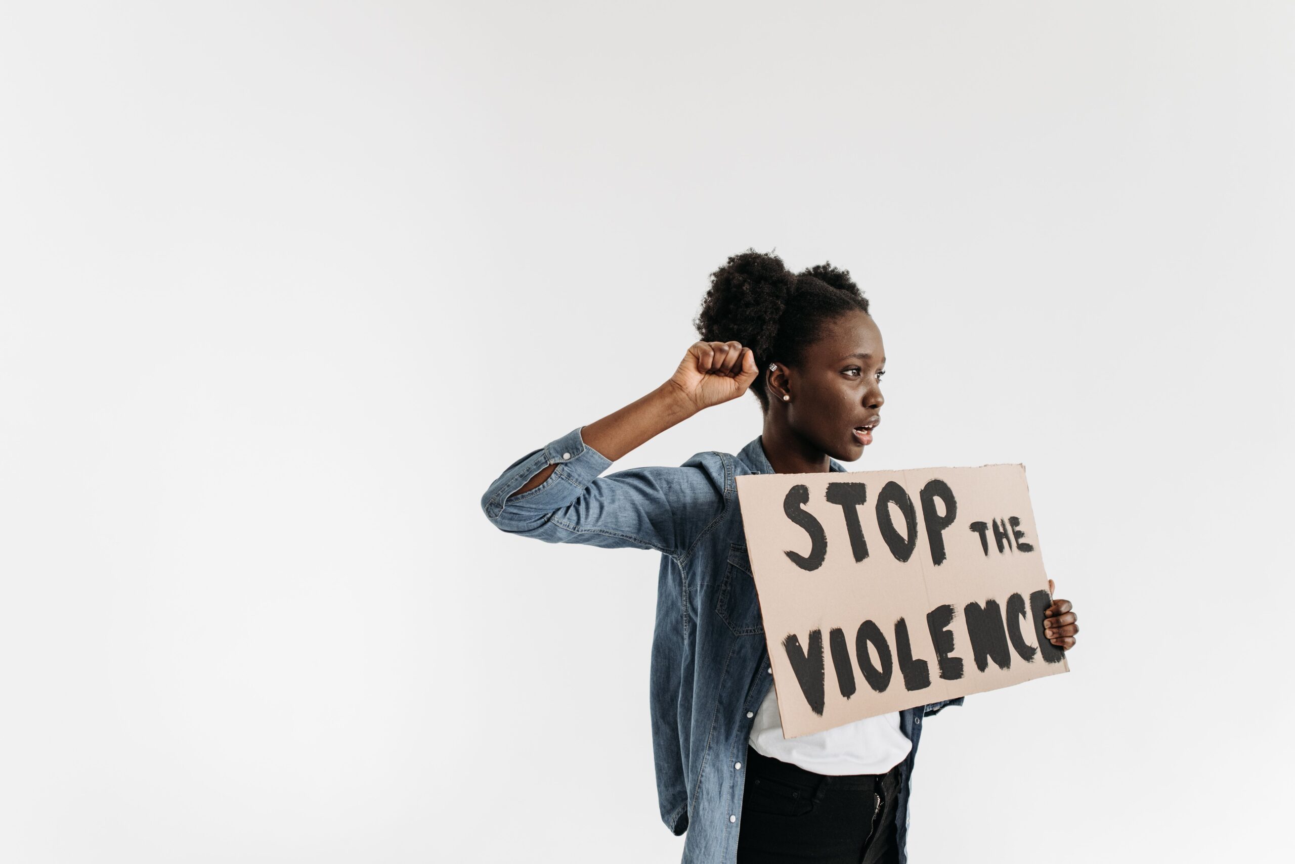 Mulher com punho erguido segurando cartaz com a frase Stop the Violence
